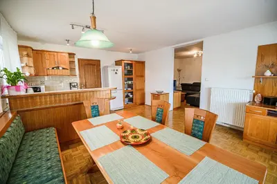 a kitchen and dining room with a wooden table and chairs at Apartments Vila Lena at Aqualuna in Podčetrtek