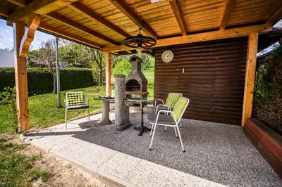 a patio with a fireplace and chairs under a wooden roof at Apartments Vila Lena at Aqualuna in Podčetrtek