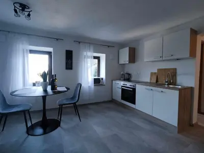 a kitchen with a table and chairs and a table and a sink at Sivka - mountain apartment with sauna in Kobarid