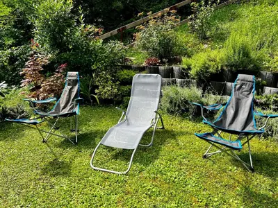 three chairs sitting in the grass in a yard at Relax in nature Apartment in Bovec