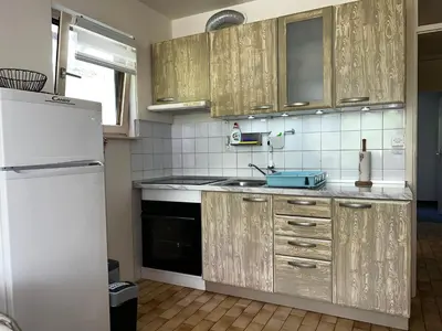 a kitchen with wooden cabinets and a white refrigerator at Relax in nature Apartment in Bovec