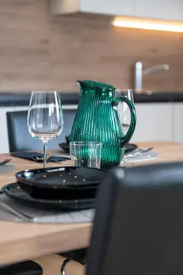 a green vase sitting on a table with glasses at Vila Katarina - Lake View Apartments in Bled