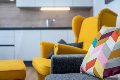 a room with yellow chairs and a colorful pillow at Vila Katarina - Lake View Apartments in Bled