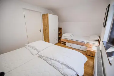 a white bedroom with a bed and a closet at Holiday Home Kozorog in Bohinj