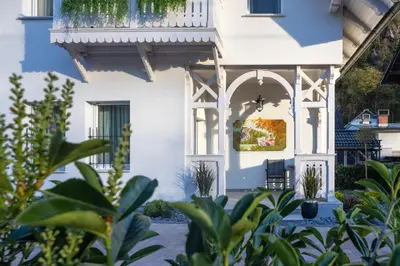 a white house with a balcony and plants at Vila Mignon in Bled
