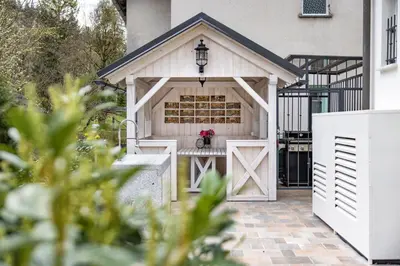 a white garage with a gate and pink flowers at Vila Mignon in Bled