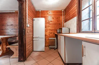 a kitchen with a white refrigerator in a room at Mala koča Wooden Cabin in Goreljek