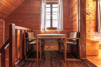 a table and chairs in a room with a window at Mala koča Wooden Cabin in Goreljek