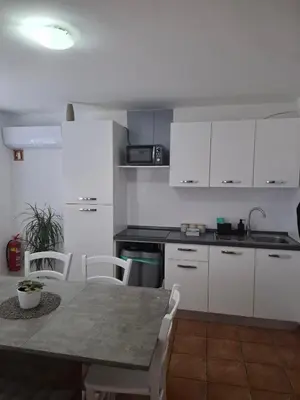 a kitchen with white cabinets and a table and chairs at Apartma Sandi in Šentilj