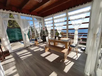 a room with a table and chairs and windows at Apartma na KOZOLCU in Dobovec