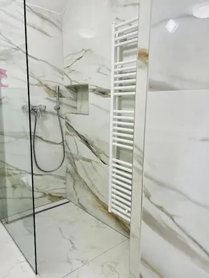 a bathroom with a shower with marble walls at City Apartment Chiara in Maribor