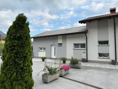 a house with a tree and some plants in a courtyard at Apartma ALTA in Tolmin