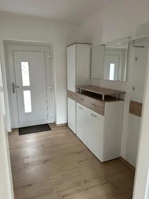 an empty kitchen with white cabinets and a door at Apartma ALTA in Tolmin