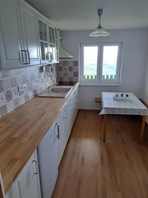 a kitchen with white cabinets and a sink and a table at Vikend hiša Vrhe in Senovo