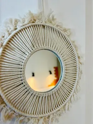 a rattan mirror hanging on a wall at Sunny app in Ljubljana