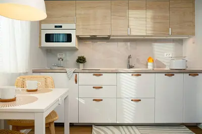 a kitchen with white cabinets and a table and a microwave at New Cute Studioapartment in Ljubljana + Free bikes in Ljubljana
