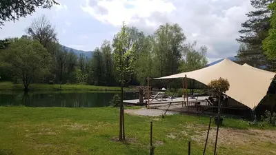 a tent in the grass next to a lake at Apartment Neli in Rečica ob Savinji
