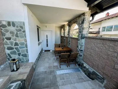 a patio with a table and chairs and a stone wall at Apartment Neli in Rečica ob Savinji