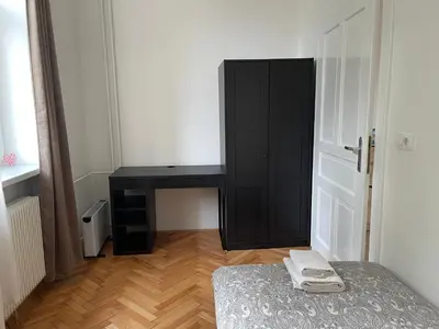 a bedroom with a desk and a bed and a black cabinet at Pirc apartment on Dunajska street in Ljubljana