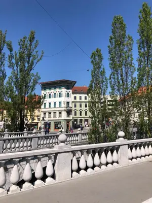 a bridge with a white building in the background at Triple Bridge Ljubljana in Ljubljana