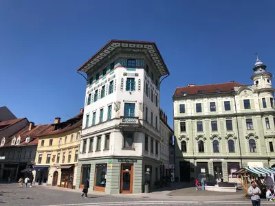a tall white building next to two other buildings at Triple Bridge Ljubljana in Ljubljana
