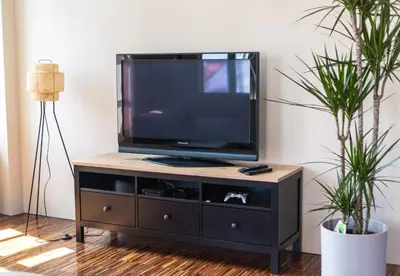 a television on a wooden stand in a living room with two plants at Triple Bridge Ljubljana in Ljubljana