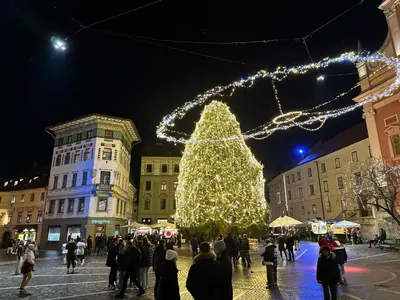 a christmas tree in the middle of a crowd of people at Triple Bridge Ljubljana in Ljubljana