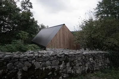 a barn with a stone fence and a stone wall at Moon - Tiny house from Callin Wines in Sežana