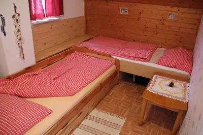 a room with two beds and a table and a stool at Mekina Guesthouse in Maribor