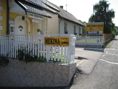 a white fence with a sign in front of a building at Mekina Guesthouse in Maribor