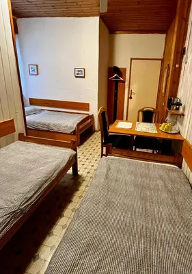 a room with two beds and a desk and a table at Mekina Guesthouse in Maribor