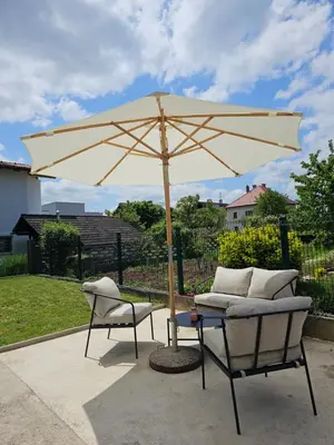 a tan umbrella and two chairs and a table at APARTMA FIREFLY1 in Ljubljana