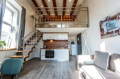 a living room with a couch and a kitchen and a staircase at The Wonderful Loft in Ljubljana