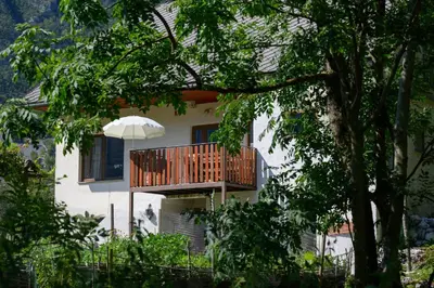 a white house with a deck and an umbrella at Stara Hiša in Log Čezsoški