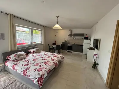 a bedroom with a large bed and a kitchen at Apartma Azurre in Postojna