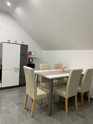 a dining room with a table and chairs and a refrigerator at Apartma Azurre in Postojna