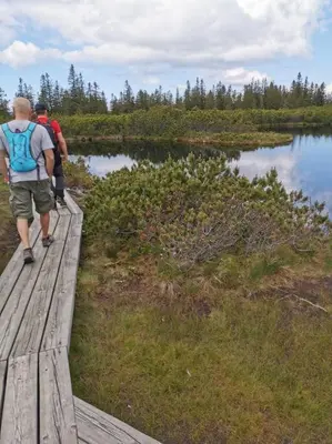two people walking on a wooden bridge over a lake at Pocket apartment Rogla - Gaber 121 in Zreče