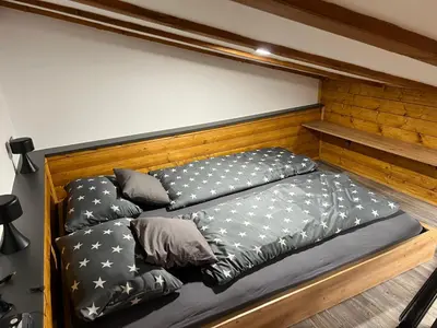a bed with black comforter and pillows on it at Apartma Mia in Črni Kal