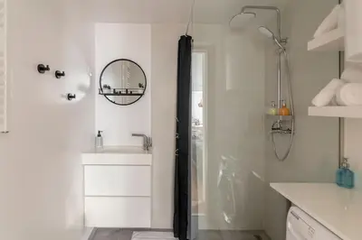 a white bathroom with a shower and a sink at Ljubljana studio with FREE parking, Washer & Dryer in Ljubljana