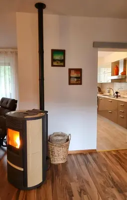 a wood stove in a living room with a kitchen at Apartma Vista montana in Kobarid