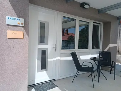 a white front door with two chairs and a table at Apartma 31 in Nova Gorica