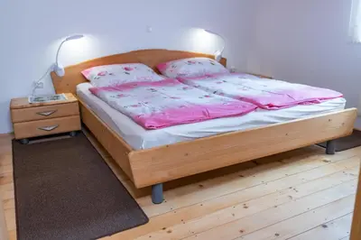 a bedroom with a bed with pink sheets and a nightstand at Apartma Metka in Bohinj