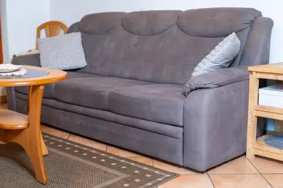 a gray couch in a living room with a table at Apartma Metka in Bohinj