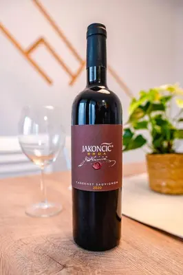 a bottle of wine sitting on a table with a glass at Apartma na hribu in Mojstrana