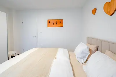 a white bedroom with a large bed with white sheets at Apartma na hribu in Mojstrana