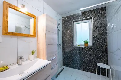 a bathroom with a shower and a sink and a mirror at Apartma na hribu in Mojstrana