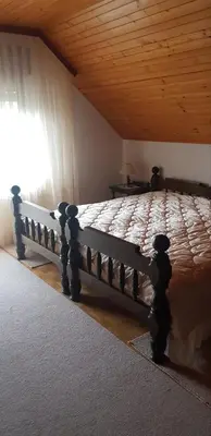 a wooden bed in a bedroom with a wooden ceiling at Apartma Sabatuš in Bohinj