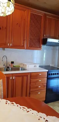 a kitchen with wooden cabinets and a sink and a stove at Apartma Sabatuš in Bohinj