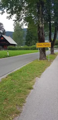 a sign on the side of a road next to a tree at Apartma Sabatuš in Bohinj
