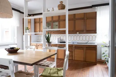 a kitchen with a wooden table and white cabinets at Passero Holiday House in Moravske Toplice